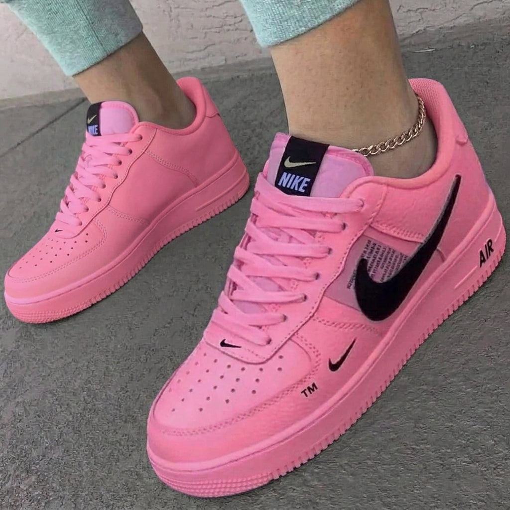 Pink Nike sneakers on a gray pavement background