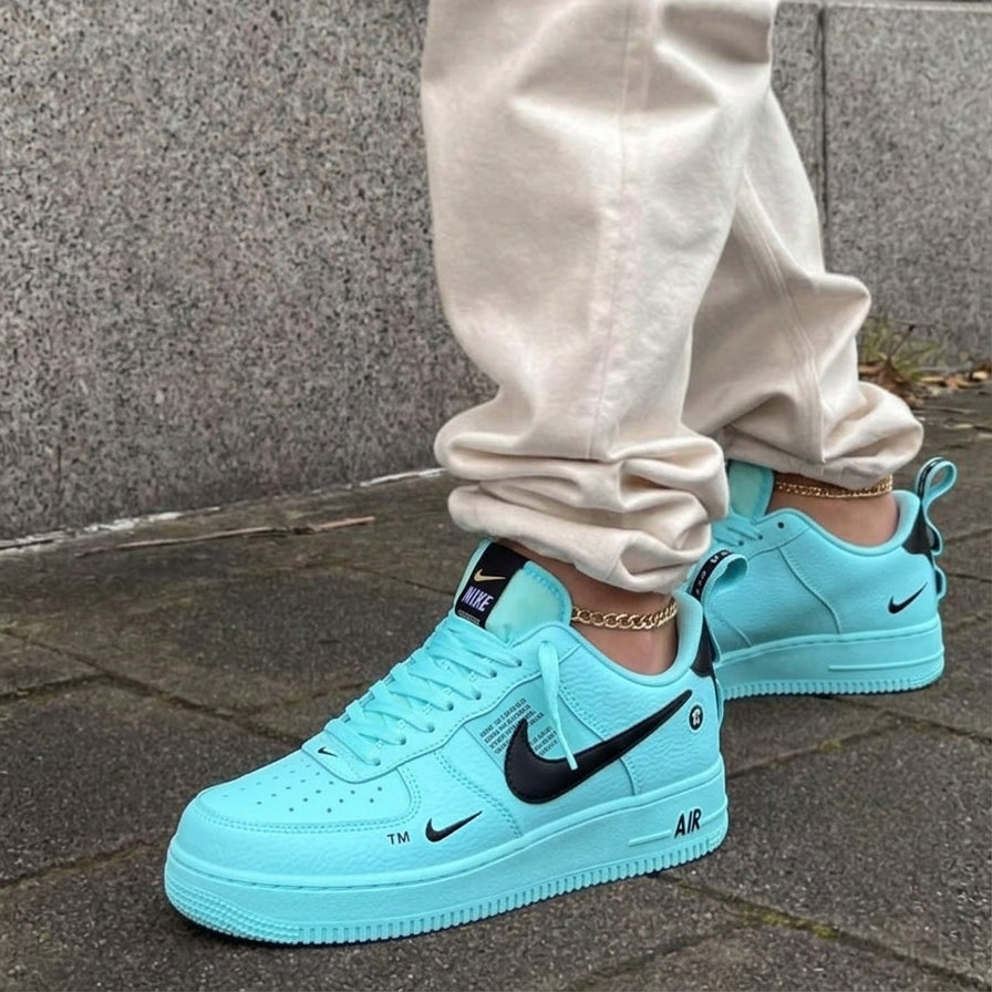 Light blue Nike sneakers with a black swoosh logo worn by a person on a stone pavement.