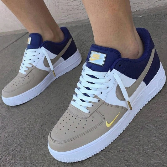 Beige and navy sneakers with white soles on a concrete surface