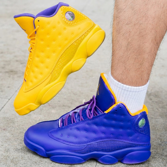 Yellow and blue sneakers worn with white socks on a concrete surface