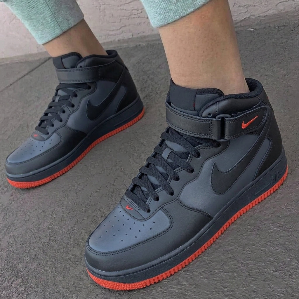 Black high-top sneakers with red soles worn on a concrete surface