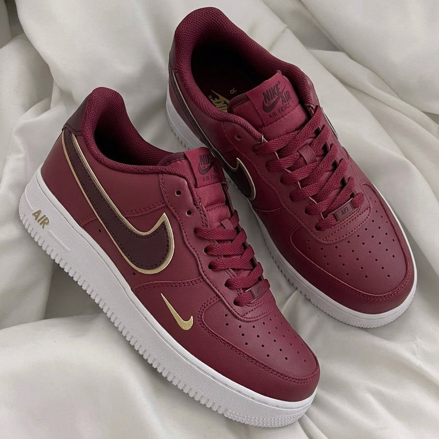 Maroon sneakers with gold Nike logo on a white fabric background